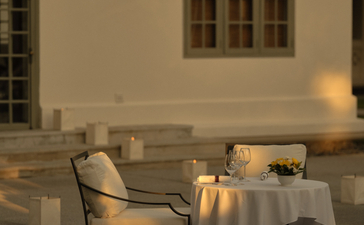 Candlelit poolside dining table at Amantaka, set for an intimate dinner beneath colonial architecture.