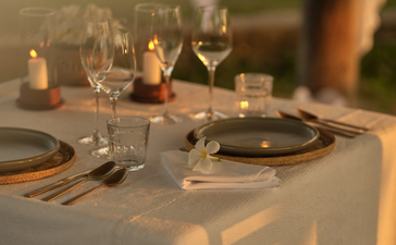 Intimate dinner table setting at Amantaka with candlelit place settings and glassware.