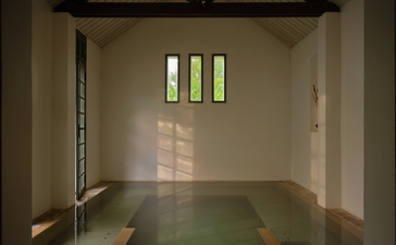 Serene bathing chamber at Amantaka with polished green floor and natural light filtering through high windows.
