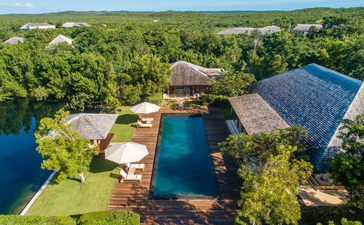 Aerial view of Tranquility Villa at Amanyara, surrounded by lush tropical vegetation and a reflection pool in Turks and Caicos.
