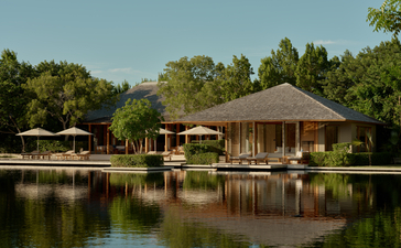 Villa overlooking tranquility pond at Amanyara, Turks and Caicos, with thatched structures reflected in still water.