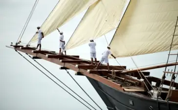Crew members on the bow of a traditional wooden sailing vessel at Amandira, Indonesia.
