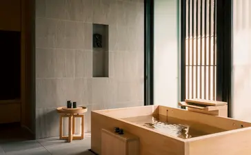 Salle de bains de la suite avec baignoire en bois massif et cloison en béton, Aman Kyoto.