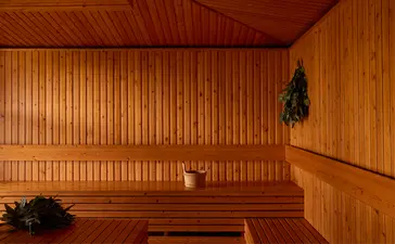 Wooden sauna interior at Amanoi with benches and warm amber lighting.
