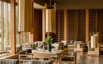 Amankora Paro Lodge living room with wooden furnishings and natural light from large windows.