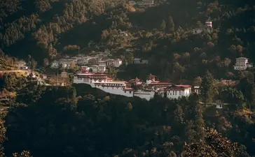 Amankora's whitewashed buildings set amongst forested hills in Bumthang valley, Bhutan.
