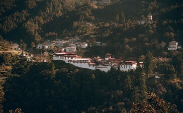 Amankora's whitewashed buildings nestled among forested hills in Bumthang Valley, Bhutan.