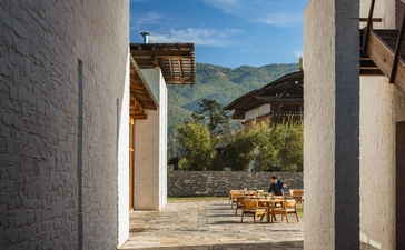 Outdoor dining pavilion at Amankora's Bumthang Lodge, framing mountain views through open stone columns.