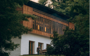 Wooden-fronted building with white-washed lower level at Amankora in Paro, Bhutan, surrounded by dense green foliage.