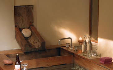 Hot stone bath at Amankora in Paro, Bhutan, with traditional wooden tub and warm lighting.