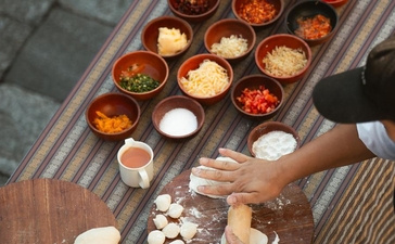 Overhead view of spices and ingredients arranged in bowls at Amankora, Punakha, with hands preparing food below.
