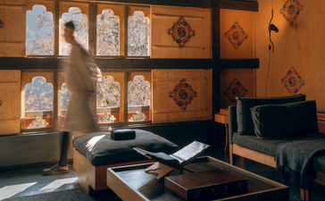 Amankora Punakha accommodation interior with wooden shelving, traditional Bhutanese artwork, and minimalist furnishings.