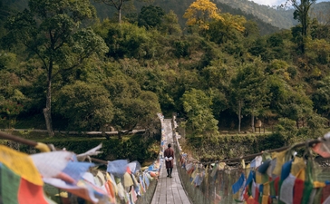 Colourful prayer flags strung across a valley at Amankora in Punakha, Bhutan, with forested mountains beyond.