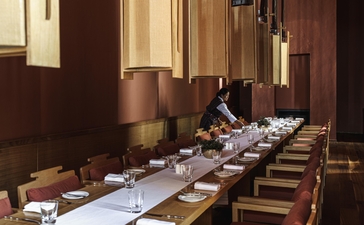 Dining room at Amankora's Bumthang Lodge with long wooden table set for a meal, warm lighting, and traditional Bhutanese décor.