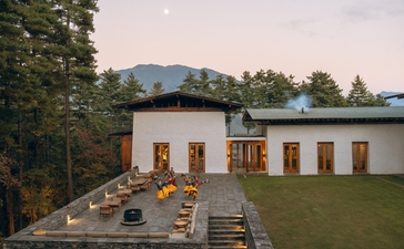 Amankora in Thimphu with wooden pavilions and seating areas on manicured grounds, mountains visible beyond.