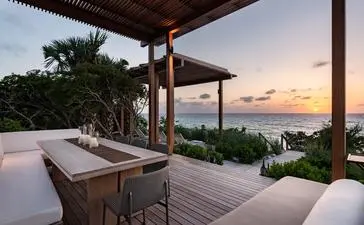Sala sulla spiaggia di Amanyara al tramonto, con vista sul mare e vegetazione tropicale.