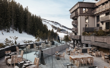Exterior terrace at Aman Le Mélézin with mountain views and snowy alpine landscape.