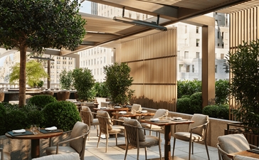 Garden terrace at Aman New York with dining tables, potted greenery, and warm wood paneling.
