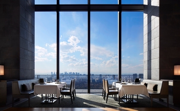 Dining room at Aman Tokyo with floor-to-ceiling windows overlooking the city skyline.