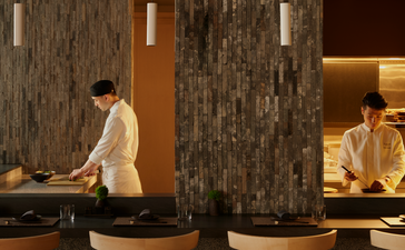 アマン ニューヨークのレストラン「名」の内装。石造りの壁と間接照明に囲まれた落ち着いたダイニングスペース。