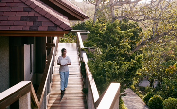 Amanpulo resort spa and wellness wooden pathway surrounded by tropical vegetation.