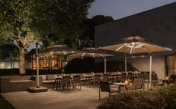 Candlelit outdoor dining pavilion at Amanyangyun at dusk, with warm lighting and seated dining areas beneath umbrellas.