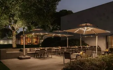 Candlelit outdoor dining pavilion at Amanyangyun at dusk, with warm lighting and seated dining areas beneath umbrellas.