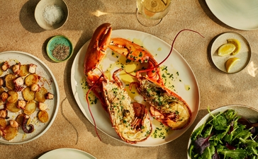 Grilled lobster with tomato and herb garnish at Amanzoe's beach club dining venue.