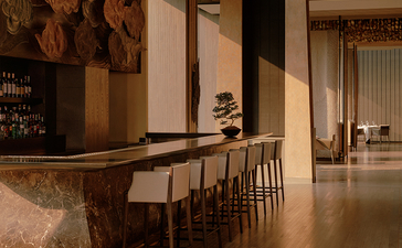 Bar at Aman Nai Lert Bangkok with wooden counter, stools, and warm ambient lighting.