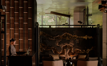 Aman Nai Lert Bangkok arrival lobby with warm lighting, brick walls, and sculptural elements.