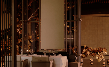Evening view of an intimate dining space at Aman Nai Lert Bangkok, candlelit and decorated with warm string lights.