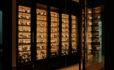 Display cabinet with illuminated shelving at Aman Nai Lert Bangkok, showcasing artefacts and objects.