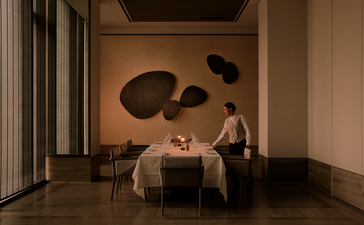 Minimalist interior at Aman Nai Lert Bangkok with two chairs facing circular wall art installations in warm lighting.