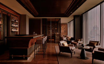 داخل حانة السيجار في أمان ناي ليرت بانكوك، تجلس منطقة جلوس دافئة بألوان بنية عميقة وأثاث جلدي.