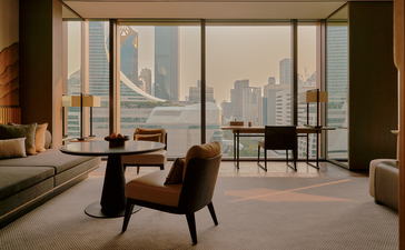 曼谷奈乐安缦酒店房间，宽敞落地窗俯瞰城市天际线，室内配有现代扶手椅和简约家具。