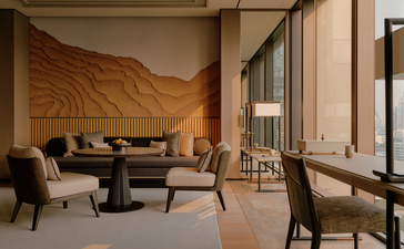 曼谷奈乐安缦酒店的房间内，土黄色墙面衬托下，深色家具和木制元素营造温暖氛围。