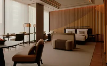 Spacious principal bedroom at Aman Nai Lert Bangkok with warm wood tones, modern furnishings, and adjoining seating area.