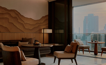 Room 176 at Aman Nai Lert Bangkok with seating area overlooking Bangkok skyline through floor-to-ceiling windows.