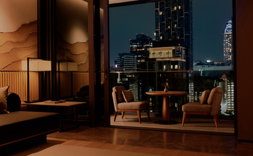 غرفة فندقية في أمان ناي ليرت بانكوك، تتميز بإضاءة دافئة وإطلالة ليلية على المدينة.