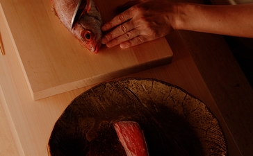Overhead view of a guest's hands arranging a woven basket at Aman Nai Lert Bangkok.
