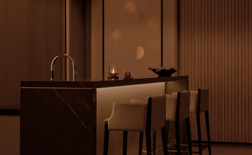 Bar area in an Aman Suite at Aman Nai Lert Bangkok, featuring a dark wooden counter with minimal furnishings and warm lighting.