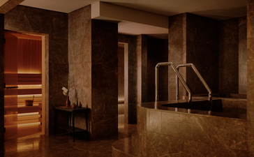 Spa suite at Aman Nai Lert Bangkok with warm wooden finishes and open-plan design.