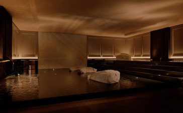 Spa treatment room at Aman Nai Lert Bangkok with dark polished floors, warm ambient lighting, and minimalist furnishings.