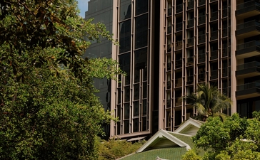 Exterior of Aman Nai Lert Bangkok with vertical timber detailing, framed by tropical greenery.