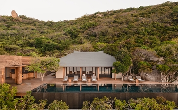 安缦诺怡度假村的海洋泳池别墅外观，坐落于绿色山坡之中。