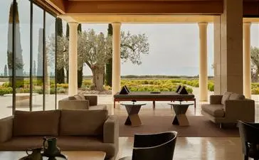 Bar lounge at Amanzoe resort overlooking the Aegean landscape through expansive windows.