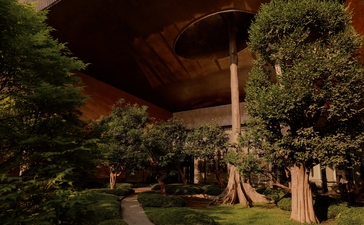 Evening view of Aman Nai Lert Bangkok's exterior with illuminated architectural features and verdant landscaping.