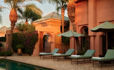 安缦珍纳度假村的Al-Hamra套房，橙色建筑立面与绿色游泳池相邻，摩洛哥建筑风格。