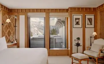 Chambre Nord bedroom at Aman Le Mélézin with wooden panelling, French doors and alpine views.