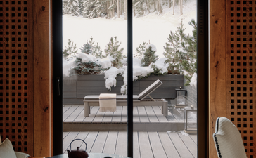Bedroom with slope views through French doors at Aman Le Mélézin, France.